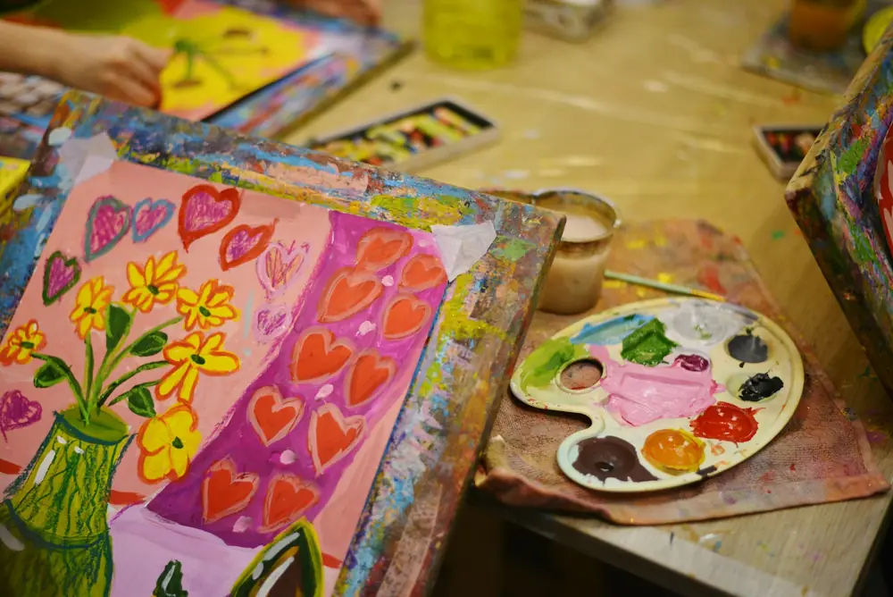 Colourful paintings and a paint palette on a table