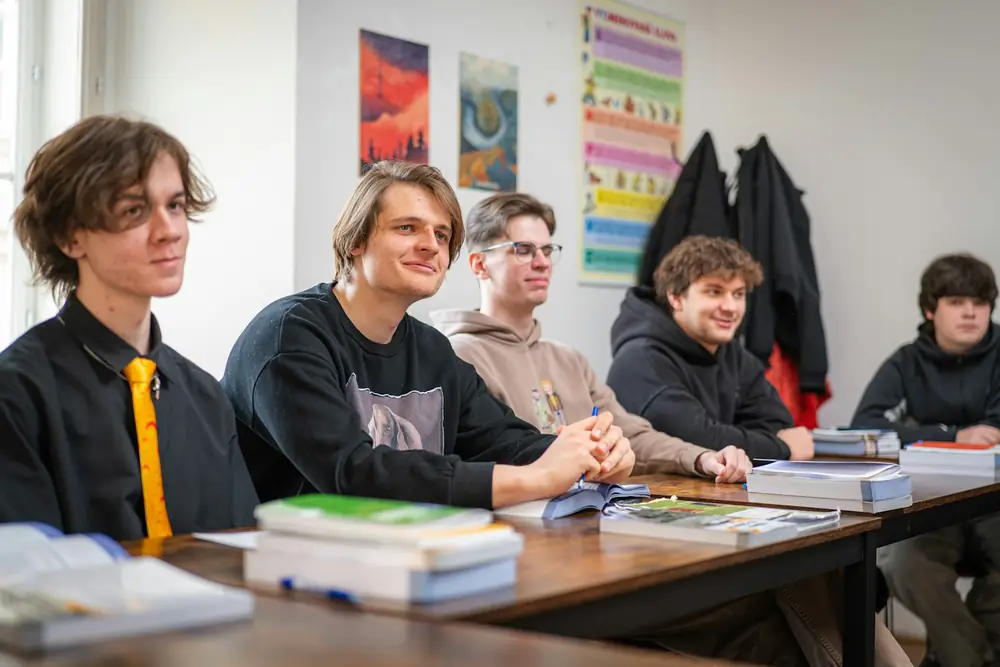 A small group of teenagers smiling around a classroom table