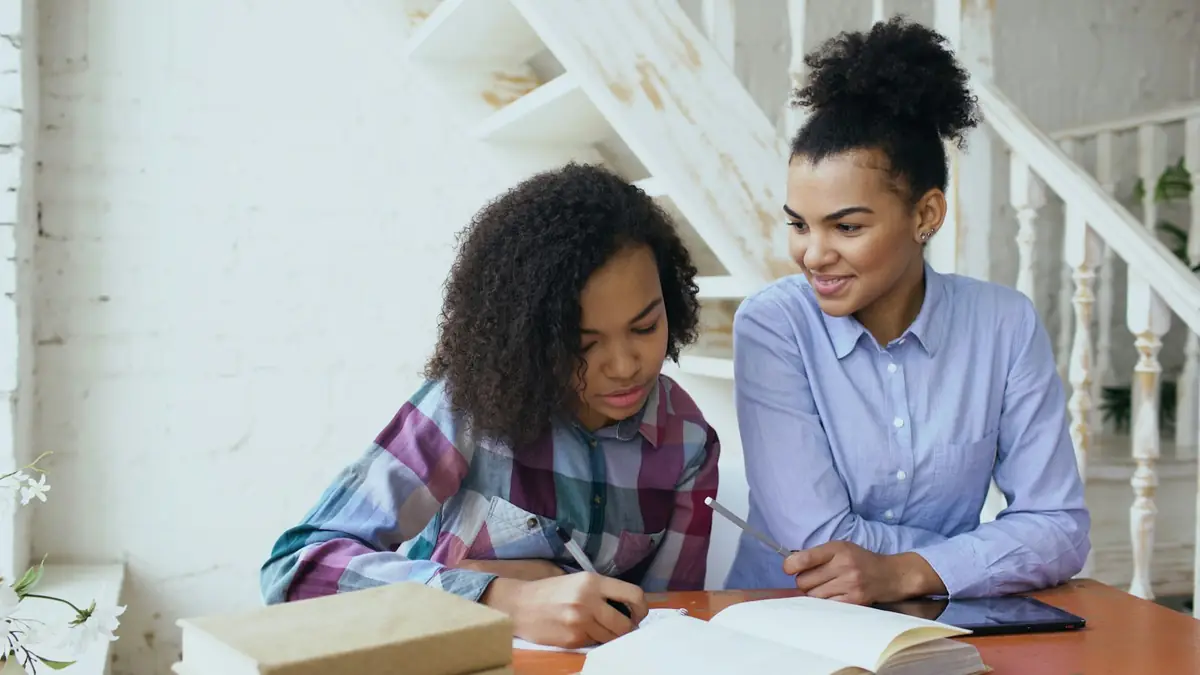 A member of staff and a young person smiling as they work through a task together